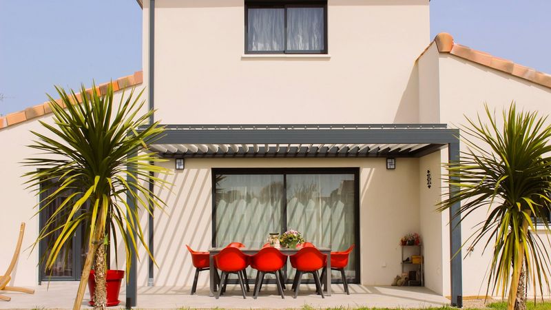 Pergola bioclimatique adossée à une maison, lames fermées