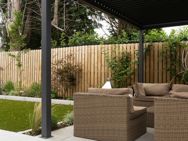 Pergola bioclimatique à lames orientables, structure sombre, dans un jardin